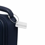 Silver luggage tag attached by a cable loop to the handle of a dark suitcase