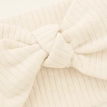 Detalle de pliegues del lazo crema acanalado y nudo textil central