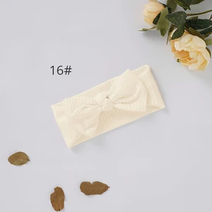Opción 16: diadema crema acanalada con lazo junto a flores y hojas decorativas