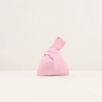 Pink cotton knot wristlet upright on an ivory tabletop