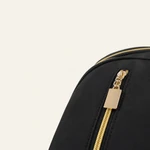 Close-up of the black backpack front pocket showing a gold-tone zipper and rectangular pull