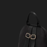 Rear close-up of the black backpack showing its top handle, webbing straps and gold-tone adjusters
