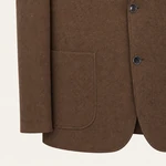 Close view of the brown blazer’s lower front, showing a patch pocket, button edge and rounded hem.