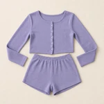 Pale-purple long-sleeve button-front top and matching elastic-waist shorts laid flat on a beige background