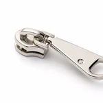 Close-up of the assembled silver-tone slider base and pull-tab connection; the pull tab grip end is cropped by the frame.