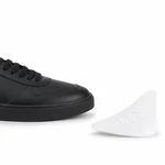 Weißer gebogener Einsatz für die Schuhspitze neben dem Vorderteil eines schwarzen Sneakers