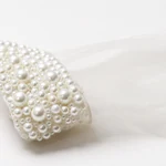 Close view of the wide pearl-style beads around a white glove cuff
