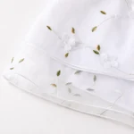 Close-up of the white floral skirt’s layered curved hem
