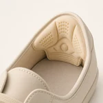 Beige heel liner placed inside the back of a closed-back shoe