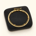 Gold anklet on a charcoal jewelry pad with clasp visible