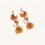 Pair of linked orange and white pumpkin earrings on a pale background