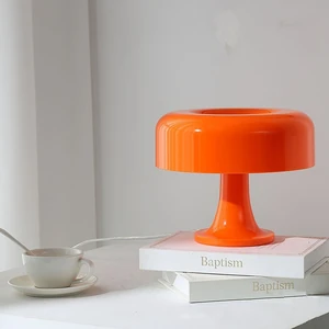 Orange mushroom table lamp with rounded recessed shade and pedestal base.