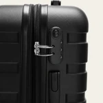 Black suitcase side close-up showing the combination lock and zipper pulls