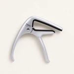 Silver guitar capo lying flat on a pale surface with its curved handles pointing down
