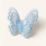 Blue embroidered organza butterfly shown from the front against a warm ivory background.