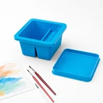 Blaues Pinselbecken und separater Deckel neben Pinseln und einem Blatt mit Aquarellmustern