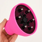 Mano sosteniendo el difusor rosa para mostrar rejilla negra perforada y dedos redondeados