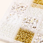 Compartiments de perles blanches à lettres, de perles imitation perle et de perles rondes dorées en gros plan