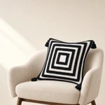 Black-and-white square-pattern cushion with corner tassels on an armchair