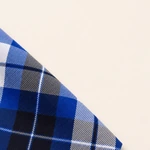 Close-up of blue plaid fabric showing diagonal woven threads at a folded edge