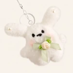 Close-up of white rabbit ears, face, green bow and cream flower