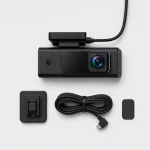 Dash camera shown with a coiled cable, separate mounting piece and small rectangular pad