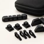 Close-up of black cable clips, a slotted holder and small straps beside a zippered case