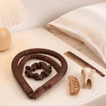 Fita para caracóis castanha e elásticos dispostos junto de um pente, ganchos e almofada