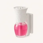 Ambientador eléctrico blanco de enchufe con un frasco transparente de líquido rosa