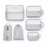 Quattro cubi da viaggio grigi con pannelli in rete accanto a una borsa per scarpe e un sacco per biancheria con coulisse