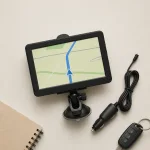 Navegador GPS visto de cima ao lado de um cabo automotivo, um caderno e chaves