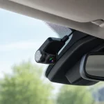 Black car camera mounted near the rearview mirror at the top of a windshield