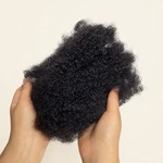 Zwei Hände halten loses dunkles Haar auseinander und zeigen die Afro-Kinky-Struktur