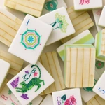 Primer plano de caras blancas de fichas de mahjong con símbolos de colores y reversos con diseño de bambú