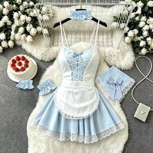 Blue and white costume laid out with dress, apron, cloth headpiece, two cuffs and a ruffled band beside photo props