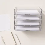 Vue du dessus de bannettes transparentes empilées près d’un carnet, d’une feuille et d’un stylo