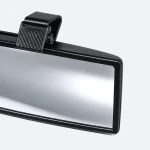 Primer plano del marco negro, la superficie reflectante y el clip superior de montaje de un espejo retrovisor.
