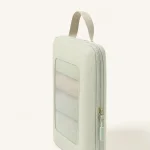 Close-up of a pale green packing cube with a mesh window, loop handle and zipper pulls