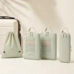 Pale green mesh-window packing cubes, slim pouch and drawstring bag beside luggage