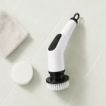 Brosse de nettoyage électrique près d'un tampon circulaire blanc séparé et d'un chiffon plié