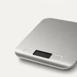 Primer plano de la pantalla de la báscula de cocina y sus dos controles bajo la superficie de pesaje.