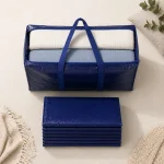 Offene marineblaue Umzugstasche mit gefalteten Textilien und darunter angeordneten flachen Taschen