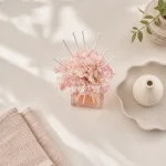Draufsicht auf einen rosa Blumendiffuser neben gefalteten Handtüchern, einem geformten Tablett und einer kleinen Vase