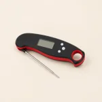 Schrägansicht eines schwarz-roten Thermometers mit neben dem Gehäuse liegender Sonde.