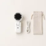 Weißer Handventilator neben einem Ladekabel und einem Zugbeutel