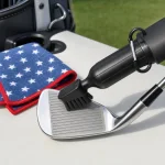 Black brush head resting against a grooved golf club face beside a folded star-patterned towel