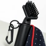 Close-up of a black golf brush showing bristles, angled neck, attachment ring and clip