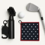 Golf brush, clip attachment and star-patterned towel arranged beside a golf ball and iron