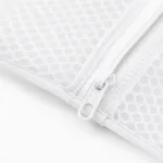 Nahaufnahme eines weissen Zippers, genähten Randes und Waben-Netzes an einem Wäschenetz