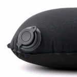 Close-up of a dark travel pillow showing a round capped valve, patterned surface and sealed edge